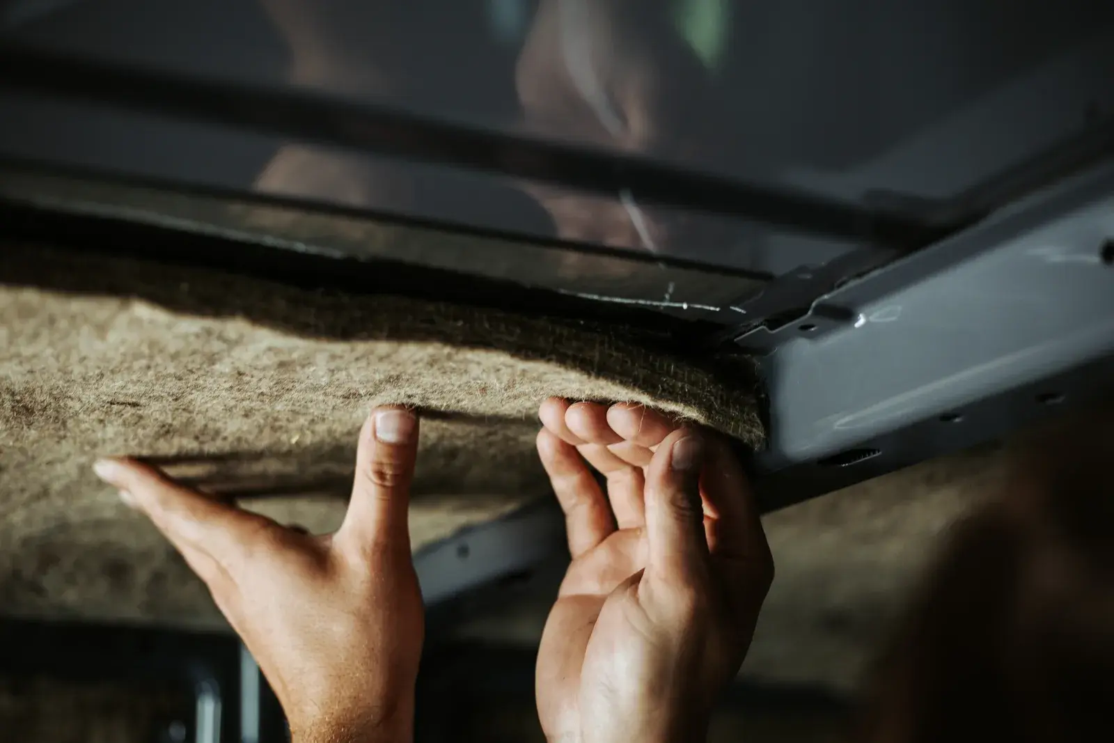 Schafwoll-Isolierung wird von Hand unter dem Fahrzeughimmel eingepasst